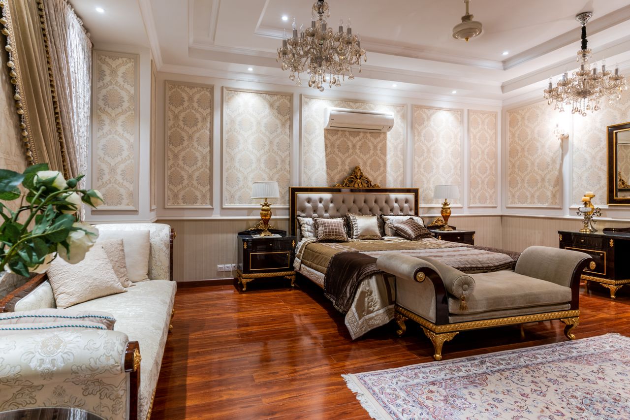 Opulent bedroom featuring a grand bed, chandeliers, and rich decor elements.